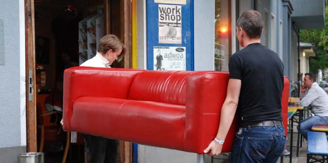 Zwei Ehrenamtliche tragen ein Sofa